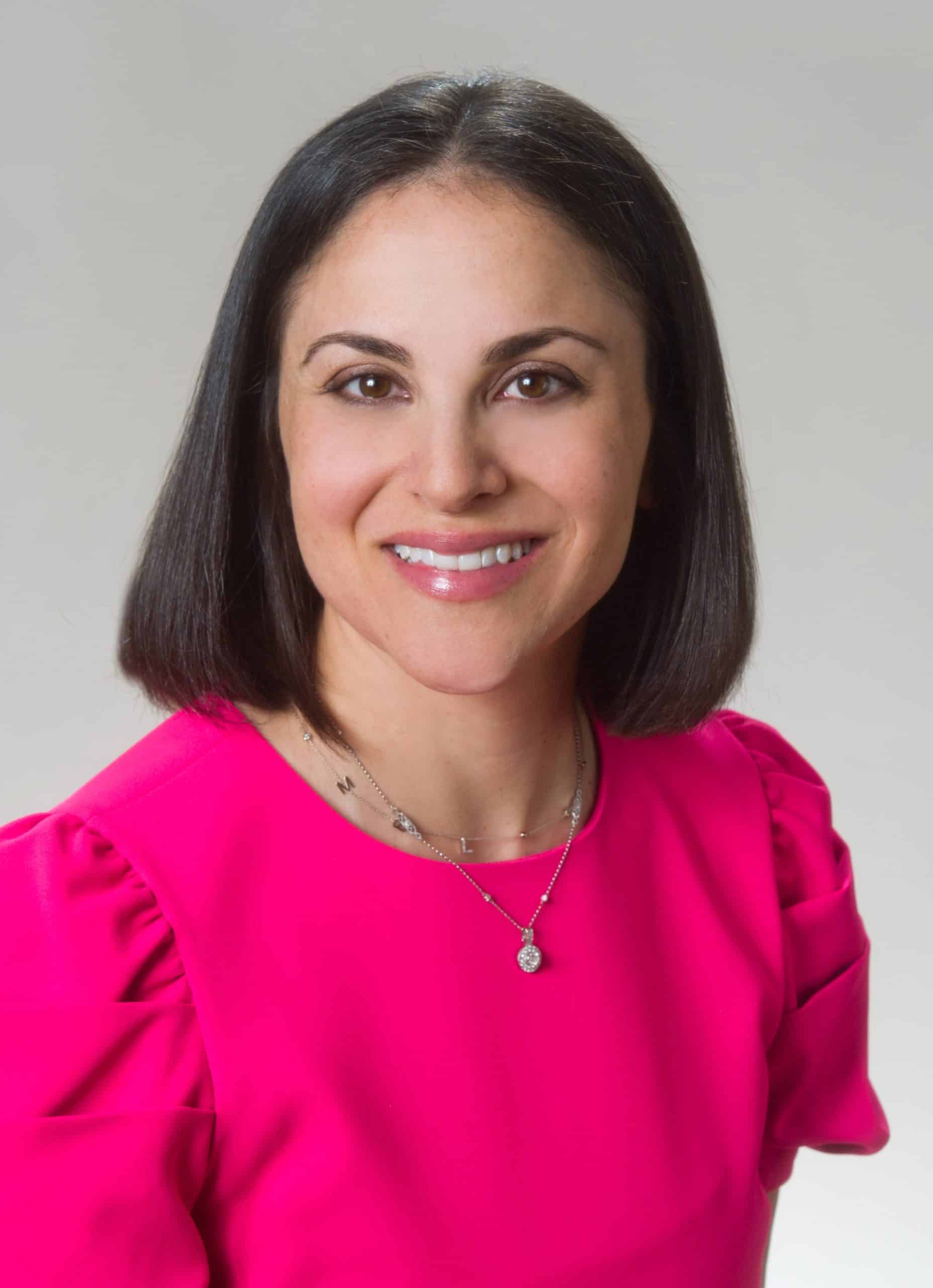 a woman wearing a purple shirt and smiling at the camera